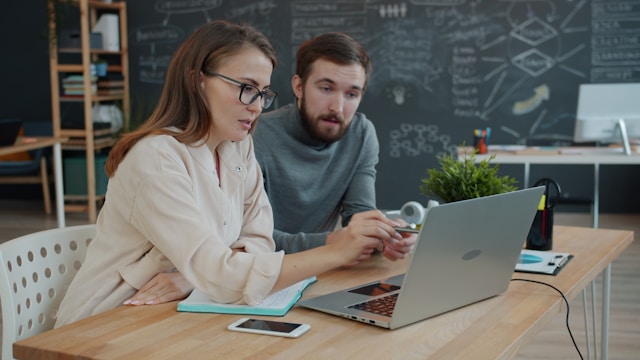 Two colleagues watching a software demo on a laptop